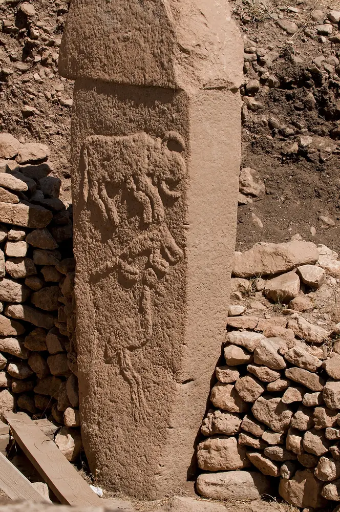 Tall T-shaped carved stone pillars standing inside an excavated circular enclosure