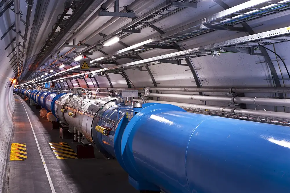 A long curved tunnel lined with blue cylindrical magnets