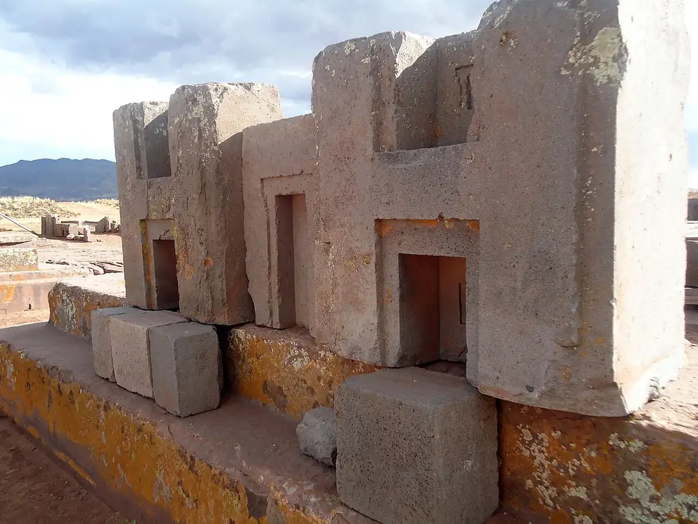 Stone blocks carved into repeating H-shaped profiles lying on the ground